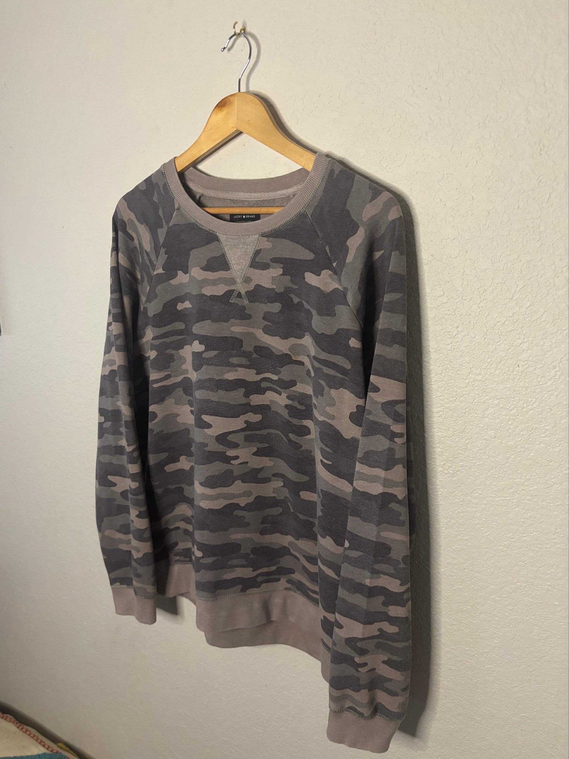 Camouflage-patterned shirt on a hanger against a plain background