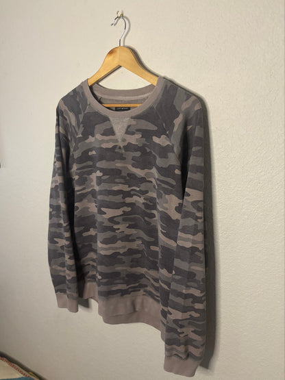 Camouflage-patterned shirt on a hanger against a plain background